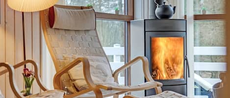 A cozy room with a fireplace, wicker chairs, and a hanging lamp.