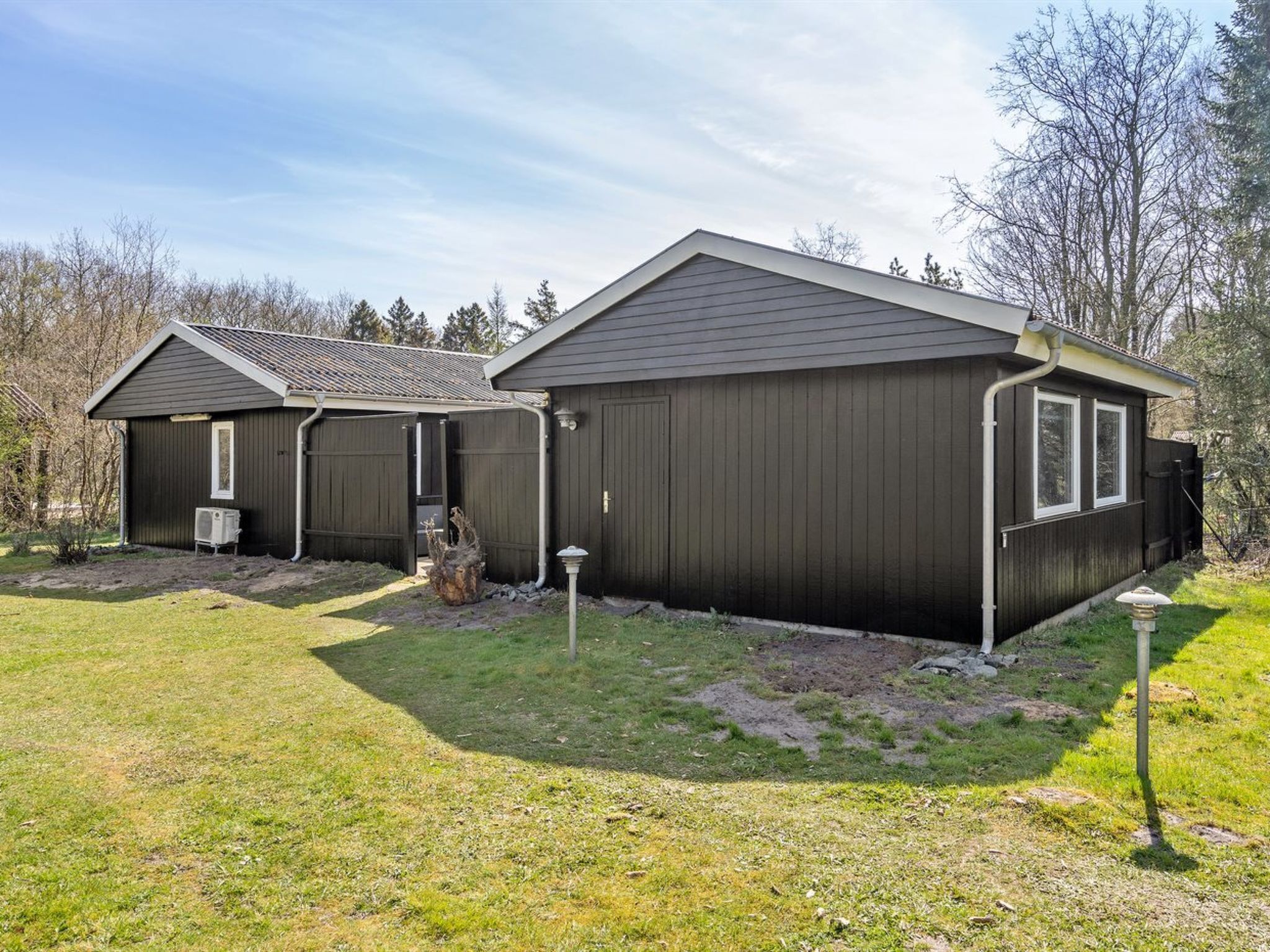 Un bâtiment à deux étages, à l’extérieur sombre, avec un garage et une petite dépendance attenante.