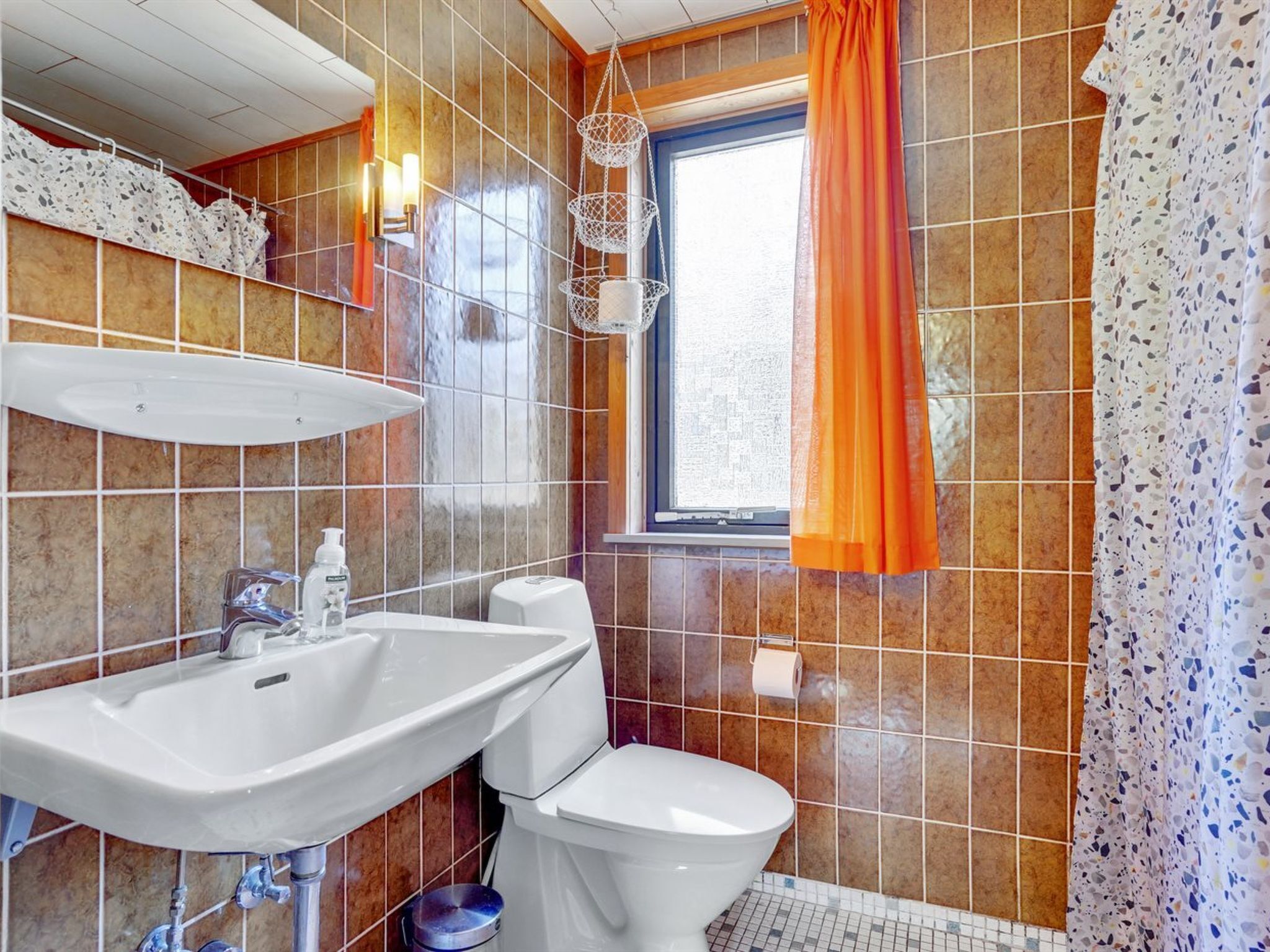 A bathroom with a sink, toilet, and window.