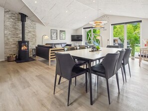 Un espace de vie moderne comprenant une cheminée, un coin repas, un canapé et un téléviseur.