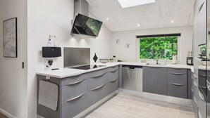 Una cocina moderna con tragaluz, electrodomésticos integrados y vistas al verdor.