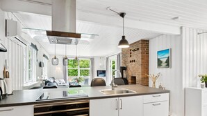 A modern kitchen with a central island, stainless steel appliances, and a brick fireplace. - "Helghi" - 30km from the sea by Interhome (Toftlund)