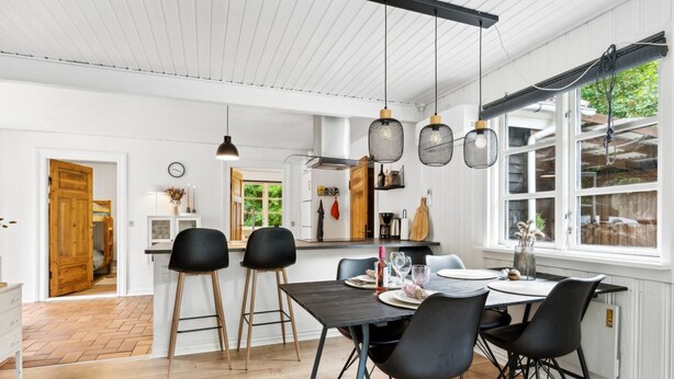 A modern kitchen with a dining area, featuring a wooden floor, black chairs, and pendant lights. - "Helghi" - 30km from the sea by Interhome (Toftlund)