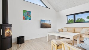 Een moderne woonkamer met een houtkachel, een bank, een salontafel en kunstwerken aan de muren.