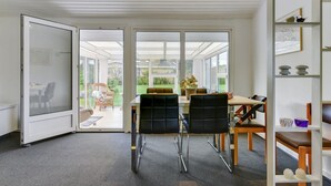Ein moderner Essbereich mit Glastür zu einem Garten, einem Tisch mit Stühlen und einem Bücherregal mit Dekoration.