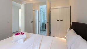 Une chambre d’hôtel avec un lit, une armoire et une salle de bain, visibles à travers une porte ouverte.