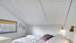 A bedroom with a bed, a window with blinds, a wall-mounted lamp, and a small bedside table. - "Gram" - 450m from the sea by Interhome (Sydals)