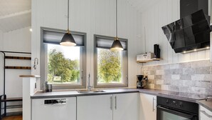 A modern kitchen with white cabinets, a black oven, and a coffee maker. - "Gram" - 450m from the sea by Interhome (Sydals)