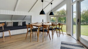A modern dining area with a wooden table and chairs, a black pendant light, and a large window offering a view of the outdoors. - "Gram" - 450m from the sea by Interhome (Sydals)