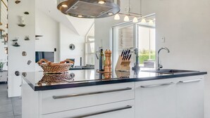 Een moderne keuken met een centraal eiland, roestvrijstalen apparatuur en een groot raam dat zorgt voor natuurlijk licht.