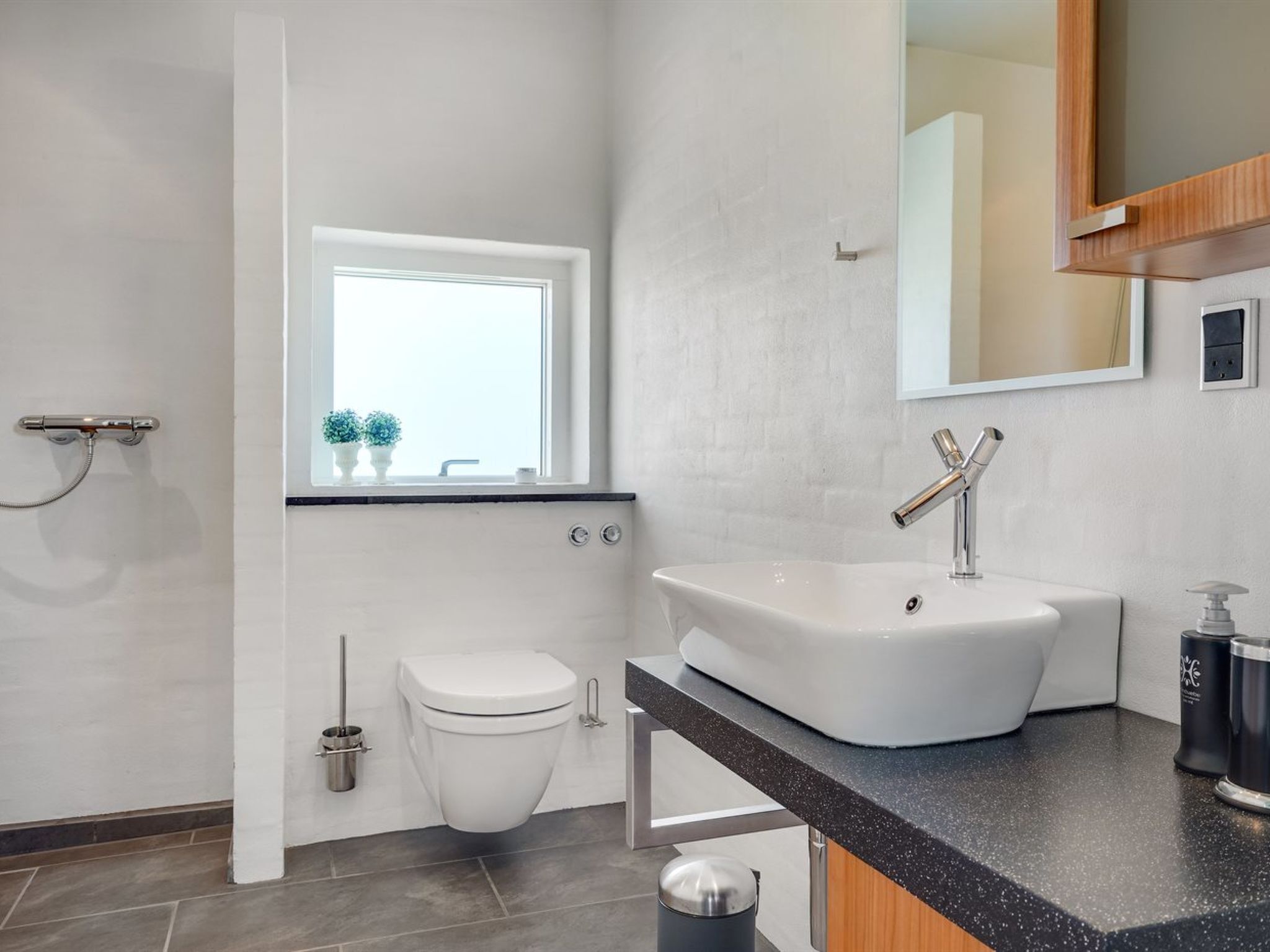 A modern bathroom with a freestanding bathtub, a toilet, and a window above the sink.