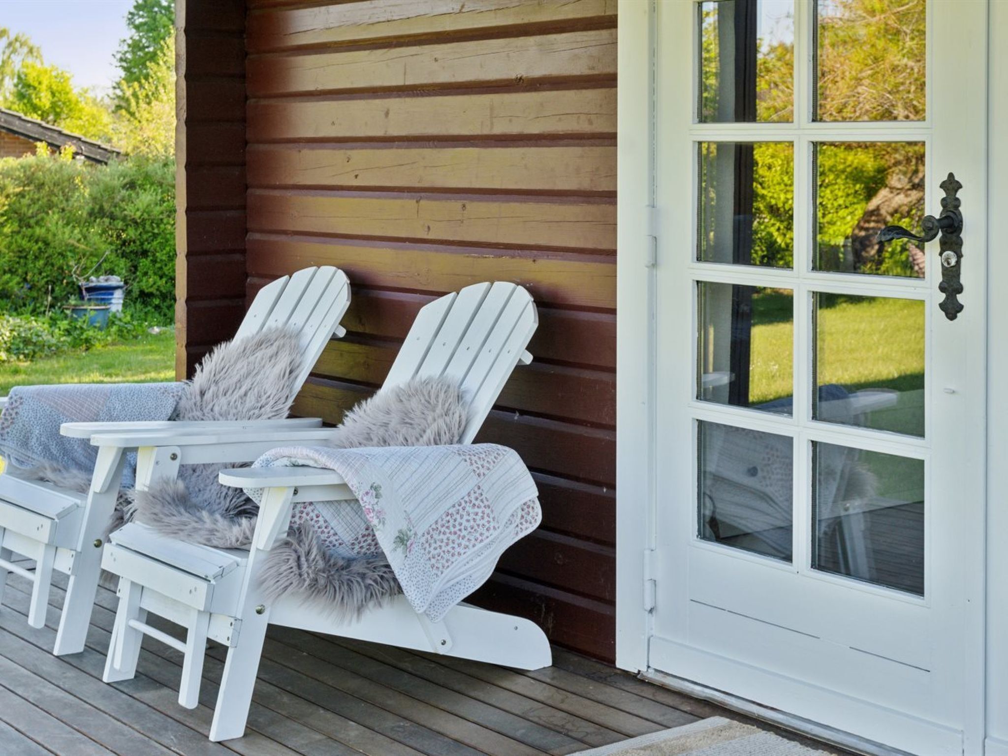 Un pontile in legno con due poltrone Adirondack, una con una coperta in pelliccia.