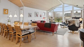 Amplia sala de estar con mesa de comedor de madera, sofá rojo y sillas modernas.