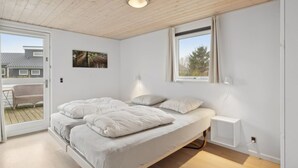 Un dormitorio con cama, ventana, un cuadro en la pared y balcón.