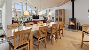 Un salón amplio con una gran mesa de madera, varias sillas, una chimenea y un televisor.