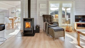 A cozy living room with a wood-burning stove, wicker furniture, and a TV.