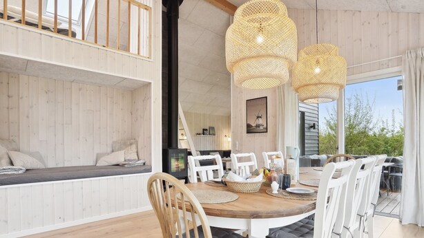 A spacious dining area with a wooden table, white chairs, and a large window overlooking greenery.