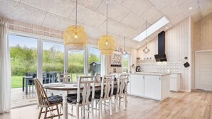 A modern kitchen with a large island, white cabinetry, and a view of the outdoors.