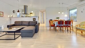A modern living room with a sectional sofa, dining table with chairs, and a kitchen area with a chimney. - "Umen" - 300m from the sea by Interhome (Sydals)