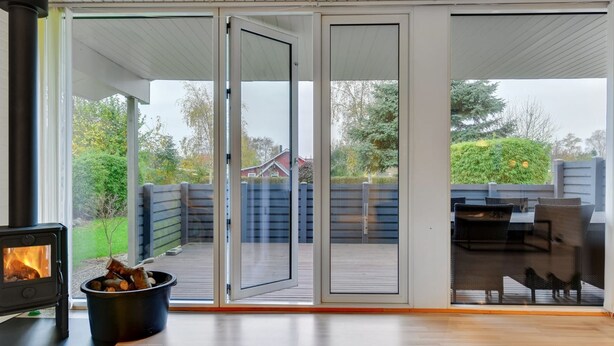 A modern living room with a fireplace, sliding glass doors leading to a deck, and outdoor furniture. - "Umen" - 300m from the sea by Interhome (Sydals)