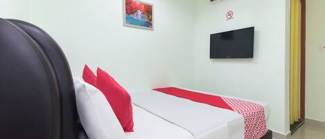 Una habitación de hotel con una cama, un televisor instalado en la pared y un equipo de aire acondicionado.