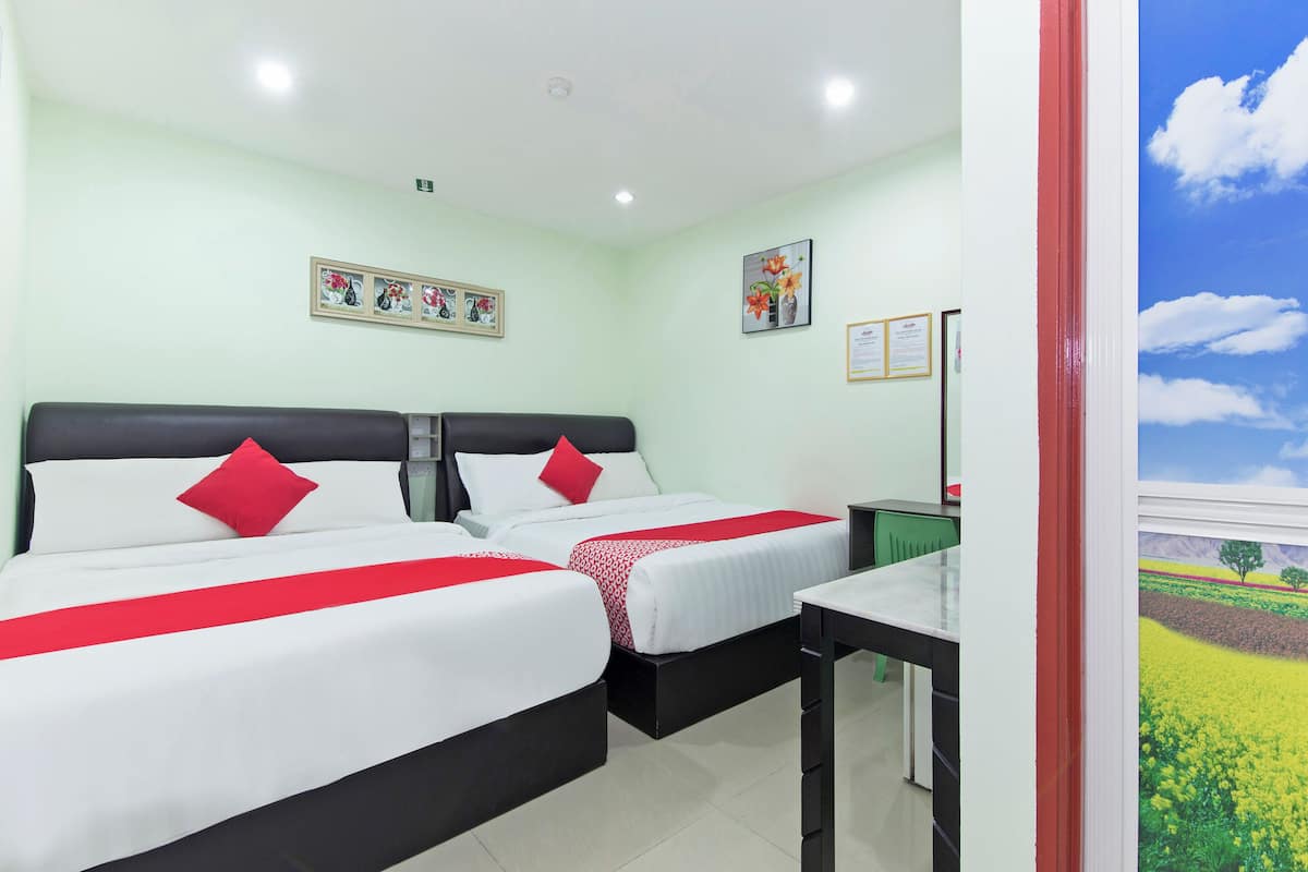 Quarto de hotel com duas camas, uma escrivaninha e vista para um campo pela janela.