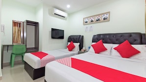 Una habitación de hotel con dos camas, un televisor, un escritorio y una silla verde.