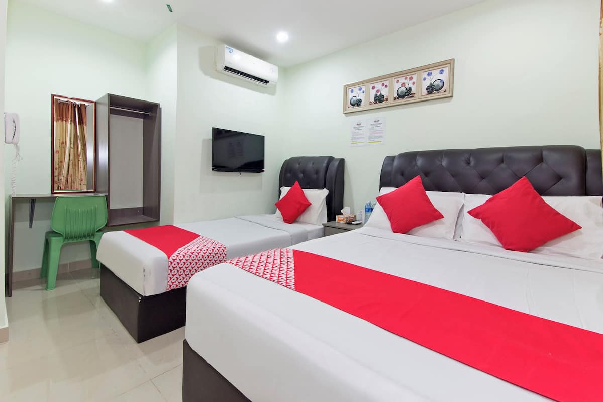 Quarto de hotel com duas camas, televisão, escrivaninha e uma cadeira verde.