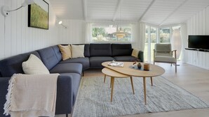 A modern living room with a dark grey sectional sofa, a round wooden coffee table, and a flat-screen TV. - "Niska" - 300m from the sea by Interhome (Sydals)