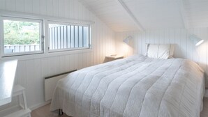 A bedroom with a large bed, a chair, a nightstand, and a window with blinds. - "Niska" - 300m from the sea by Interhome (Sydals)