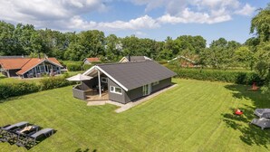 A modern house with a large deck, surrounded by a well-maintained lawn and trees. - "Niska" - 300m from the sea by Interhome (Sydals)