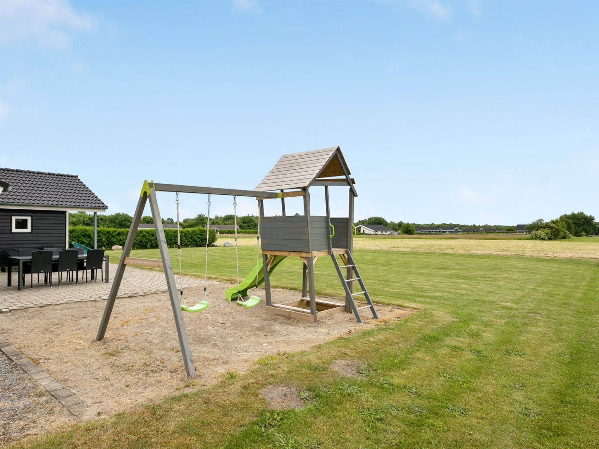 A playground with a swing set and a wooden playhouse.