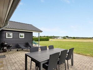 A patio with a table and chairs, a grill, and a small house with a tiled roof. - "Finja" - 500m from the sea by Interhome (Sydals)