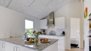 Eine moderne Küche mit Granit Arbeitsplatten, weißen Schränken und einem großen Fenster für natürliches Licht.