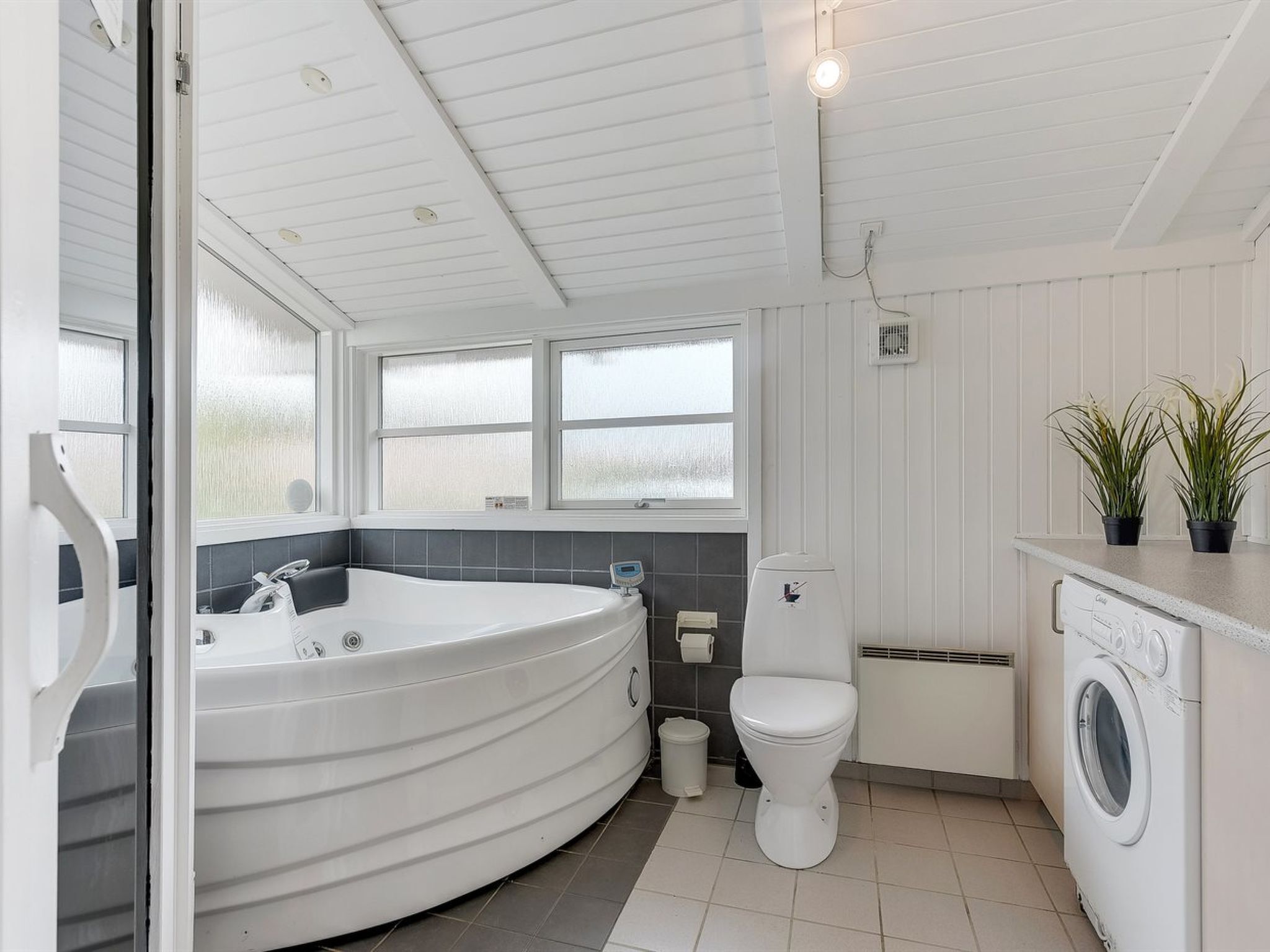 A modern bathroom with a freestanding bathtub, a toilet, and a washing machine.