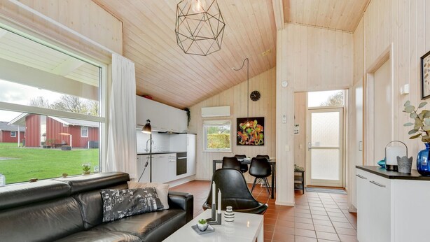 Een moderne woonruimte met een zwarte leren bank, een witte salontafel en een eethoek met zwarte stoelen.