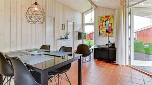 Een moderne eetruimte met een glazen tafel, zwarte stoelen en een geometrische hanglamp.