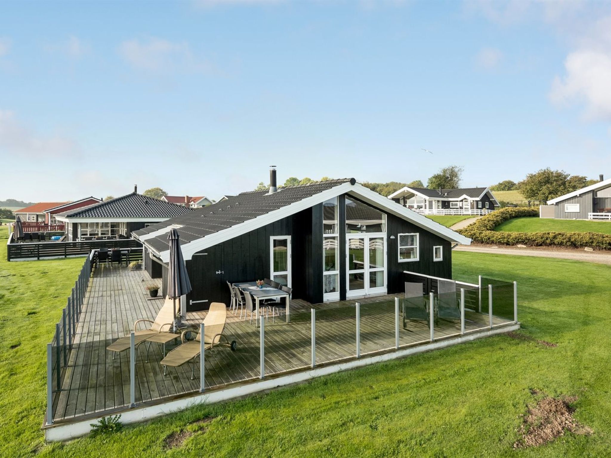 Een modern huis met een houten terras en een patio met glazen wanden.