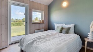 Ein Schlafzimmer mit einem großen Bett, einem Fenster und einer wandmontierten Leuchte.