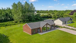 Een modern gebouw met een grote glazen gevel, omringd door een verzorgd gazon en bomen.