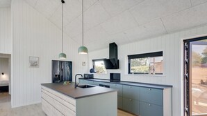 Een moderne keuken met een centraal eiland, hanglampen en uitzicht op de omgeving.