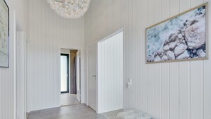Een gang met een bank, een deur en een schilderij aan de muur.