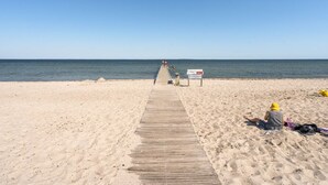 Een houten looppad naar een strand, met een heldere lucht.
