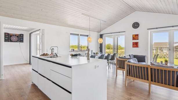 Une cuisine moderne dotée d’un îlot central, d’un coin repas offrant une vue agréable et d’un espace de vie avec une grande fenêtre.