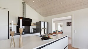 Une cuisine moderne avec des meubles blancs, un évier en acier inoxydable et un plan de travail noir.