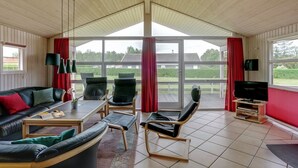 Een ruime woonkamer met een groot raam, een bank, een salontafel en een televisie.