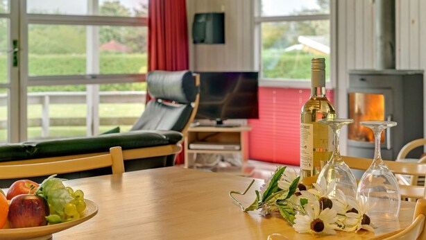 Een gezellige kamer met een houten tafel, een bank, een televisie en een open haard.