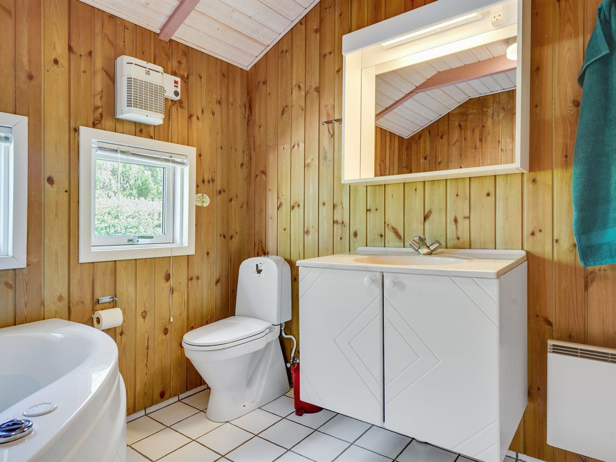 Een betegelde badkamer met toilet, wastafel en bad.