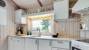 A kitchen with wooden cabinets, a window with a view, a sink, and a stove. - "Guldborg" - 400m to the fjord by Interhome (Egernsund)