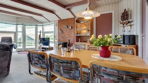 A dining area with a wooden table, chairs, and a red vase with flowers. - "Guldborg" - 400m to the fjord by Interhome (Egernsund)